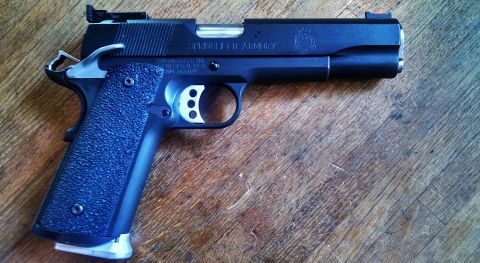 1996 Ford Bronco - A Springfield Armory 1911 pistol rests on a wooden surface, showing its detailed construction and markings.