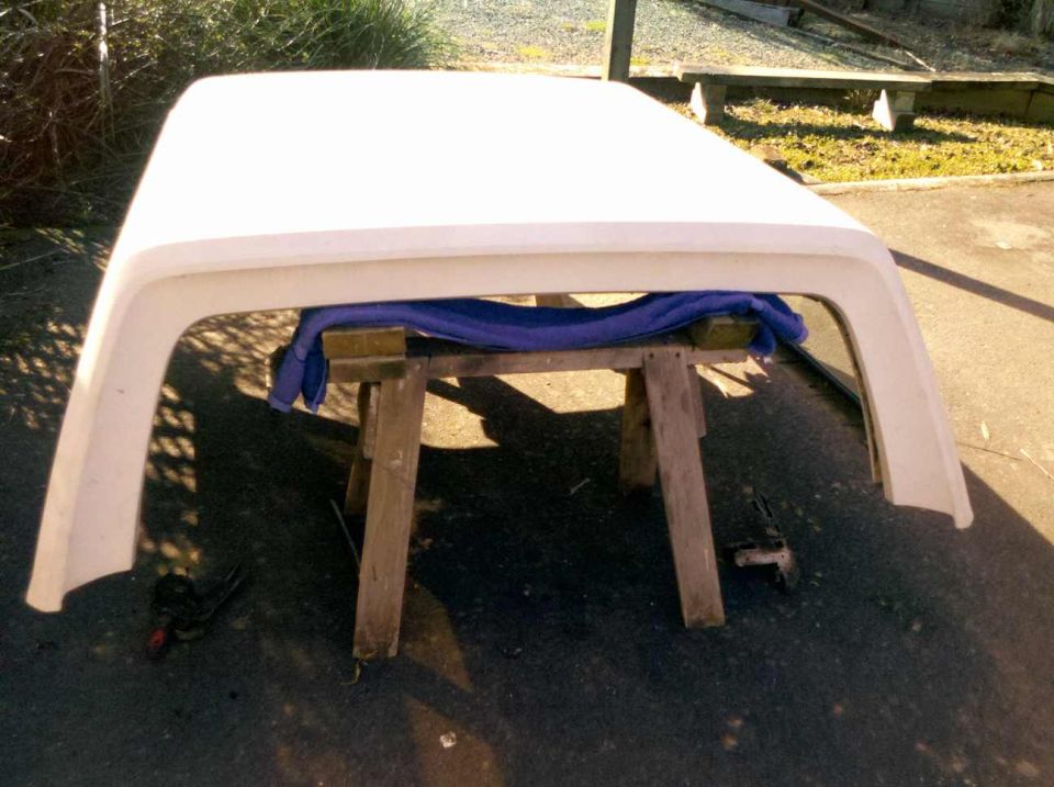 White truck cap resting on wooden sawhorses outdoors