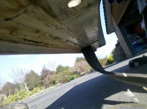 1982 Ford Bronco - A low-angle shot reveals the underside of a vehicle's fender and a tire, with a garage in the background.