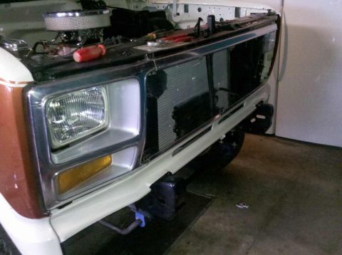 1982 Ford Bronco - Front view of a white and brown Ford Bronco showing its grille and headlights during a rebuild.