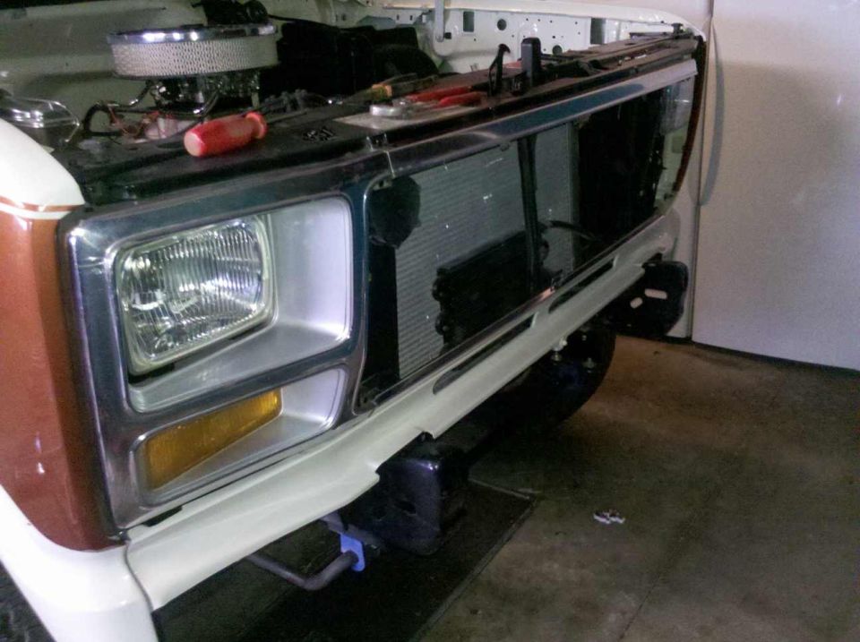 White and brown Ford Bronco front end with chrome grille and square headlights, undergoing repairs