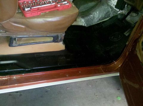 1982 Ford Bronco - Socket set rests on the seat of a vehicle undergoing interior work, revealing the floor and door sill.