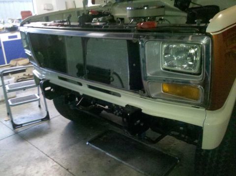 1982 Ford Bronco - Front view of a 1982 Ford Bronco undergoing repairs, with the hood raised to reveal the engine compartment.