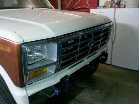 1982 Ford Bronco - The front of a Ford Bronco, showing its grille and headlight assembly, is parked indoors.
