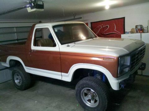 1982 Ford Bronco - This two-tone Ford Bronco, likely from the early 1980s, is shown in a garage with visible aftermarket modifications.
