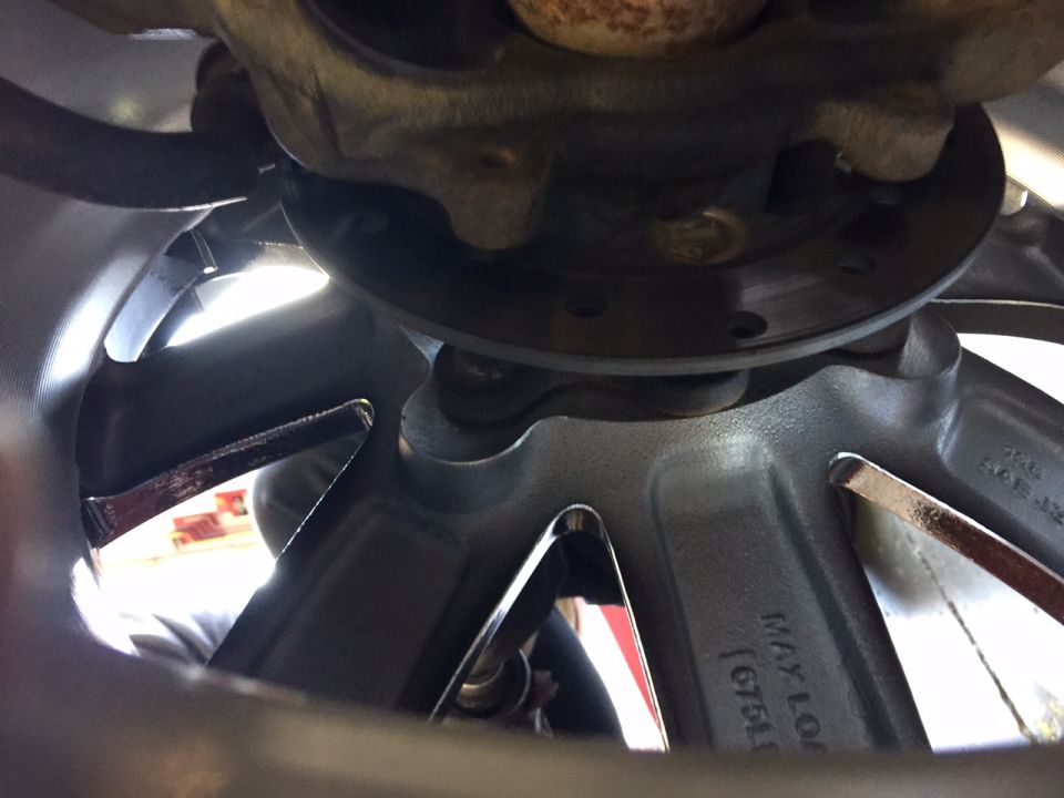 Close-up of a vehicle's wheel hub and brake rotor with visible text 'MAY LO 1675'