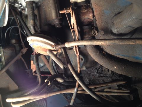 1973 Ford Bronco - Close-up view of engine bay components, including various hoses and cables, with visible rust and dirt.
