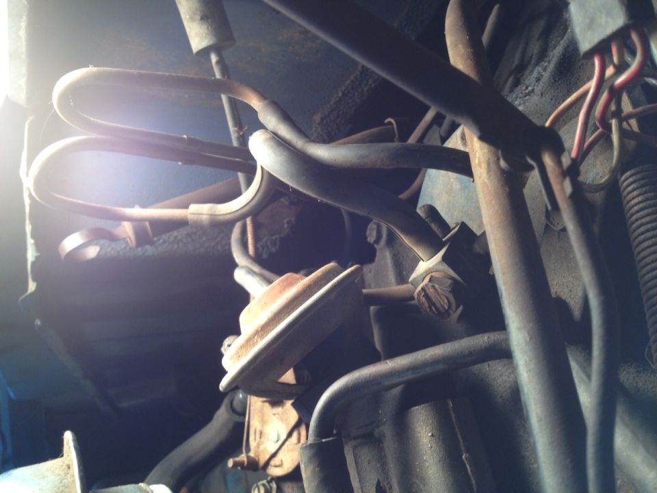 Engine bay with metal tubes, wires, and a rusty component
