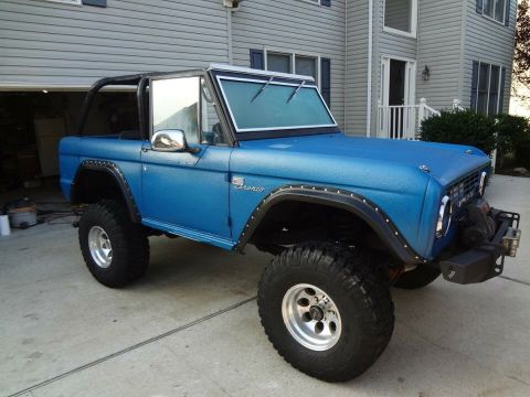 1974 Ford Bronco - This blue Ford Bronco has a textured paint job and large off-road tires.