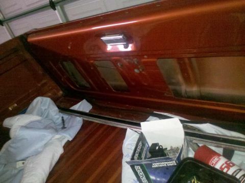 1982 Ford Bronco - Interior view of an orange vehicle, possibly a Bronco, with a chrome handle and windows. A box of abrasive discs is also present.
