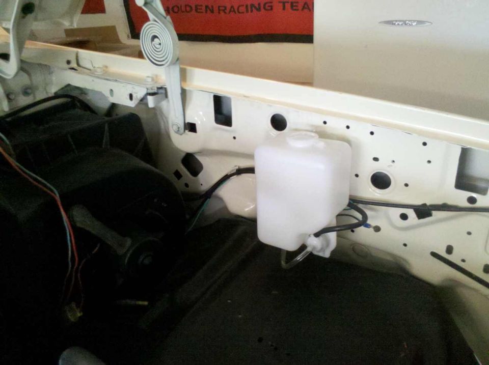 Windshield washer fluid reservoir and wiring in an engine bay. Supermotors.net logo visible