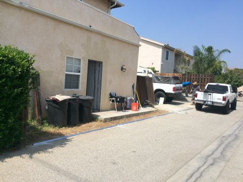 1968 Ford Mustang - Two white pickup trucks are parked on a street in front of a house with trash cans and fencing nearby.