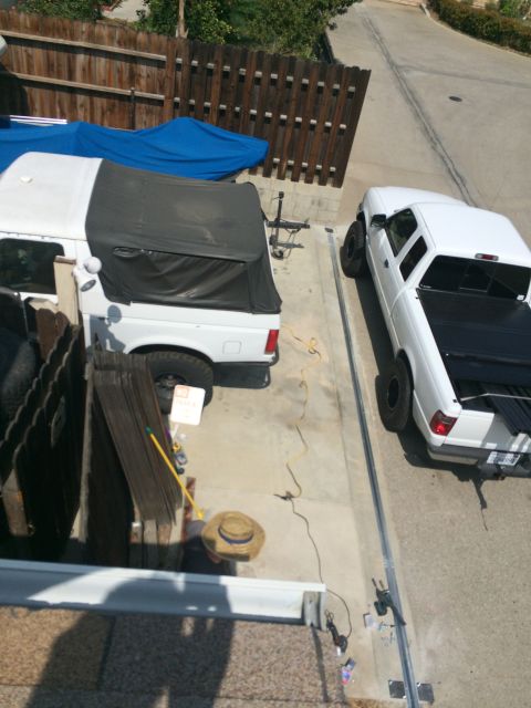 1968 Ford Mustang - Two white pickup trucks are parked side-by-side on a concrete driveway, with a wooden fence in the background.
