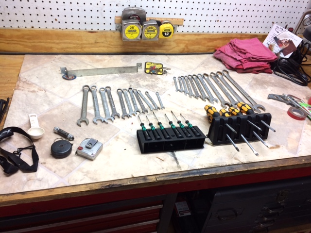 Workbench with wrenches, screwdrivers, tape measures, and rags