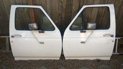 1994 Ford Bronco - Pair of white truck doors, likely for a Ford F-series or Bronco, displayed outdoors.