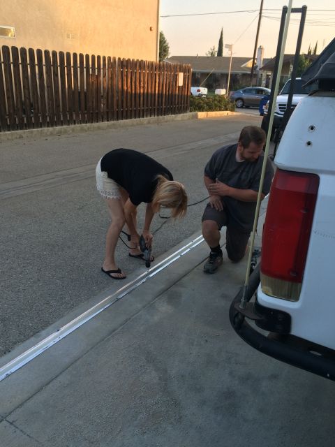 1968 Ford Mustang - Two people are working on a metal track installed along the edge of a driveway.