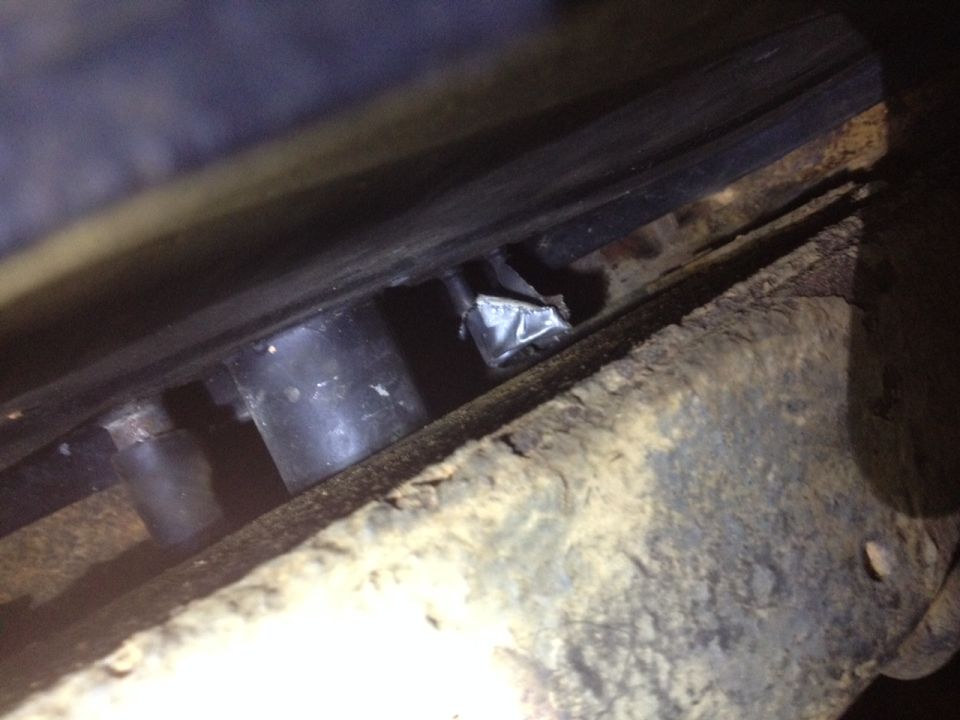 close-up of rusty metal and black cylindrical parts under a vehicle