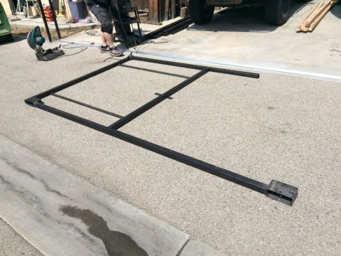 1968 Ford Mustang - A metal frame is laid out on an asphalt surface, with a chop saw and a person visible in the background.