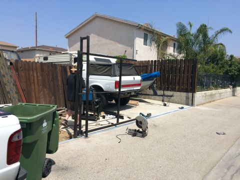 1968 Ford Mustang - A white Ford F-Series truck is parked in a driveway, hitched to a boat on a trailer, with a camper shell covering the truck bed.