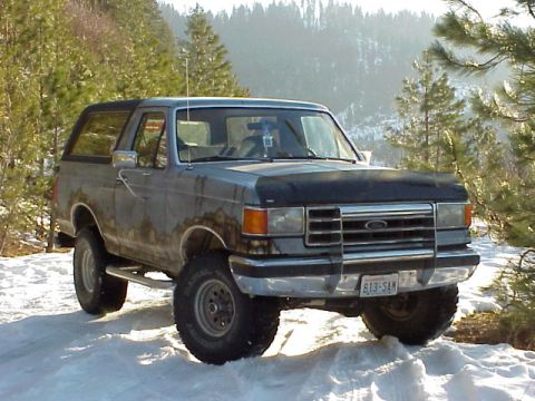 1989 Ford Bronco - A gray 1989 Ford Bronco sits in the snow, its front end angled towards the viewer.