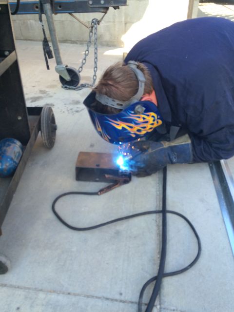 1968 Ford Mustang - A person is welding a piece of metal on the ground.
