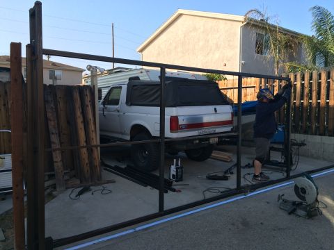 1968 Ford Mustang - A person is welding a metal fence in a driveway next to a white Ford Bronco.