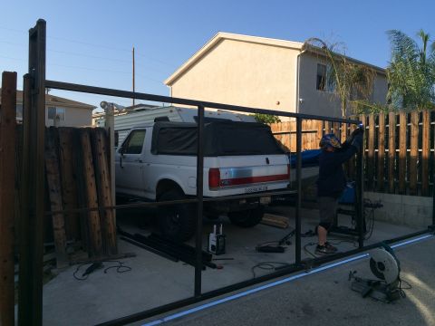 1968 Ford Mustang - A white Ford Bronco is parked in a driveway while a person welds a metal gate.