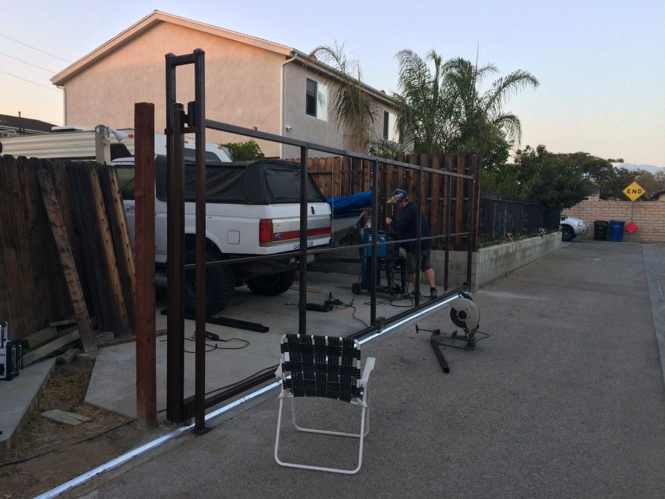 White Ford F-Series pickup truck, likely 1992-1996, parked in a driveway with a gate construction project underway