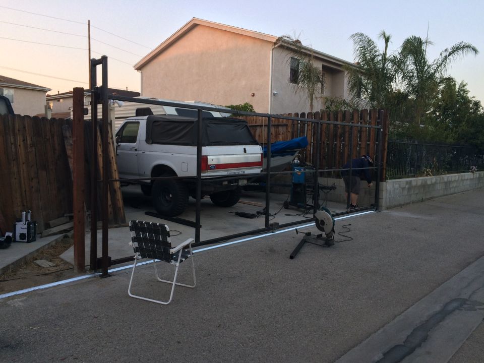 White pickup truck with camper shell parked near a fence being worked on