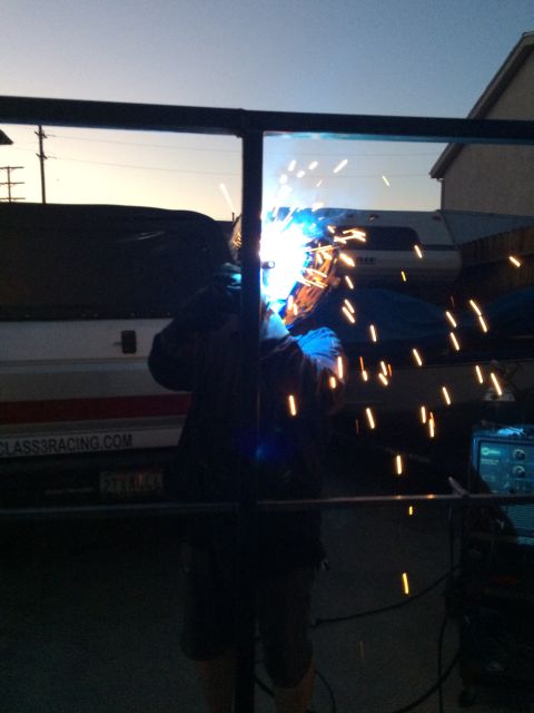 1968 Ford Mustang - A person is welding in front of a vehicle at dusk. Sparks are flying from the welding torch.