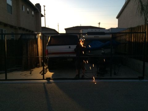 1968 Ford Mustang - A white pickup truck with a camper shell is parked in a driveway, with a person welding in front of it.