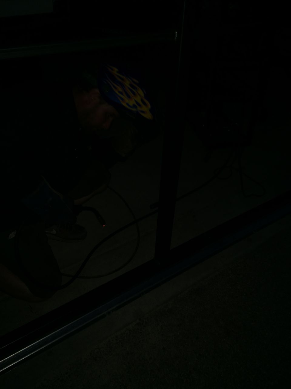 Person wearing a welding mask and helmet, welding with a torch, with cables on the floor