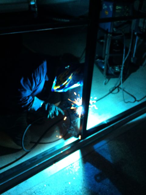 1968 Ford Mustang - A welder works on a metal structure, illuminated by the bright sparks from their welding torch.