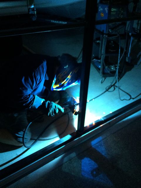 1968 Ford Mustang - A welder works on a metal structure, illuminated by the bright sparks of their torch.