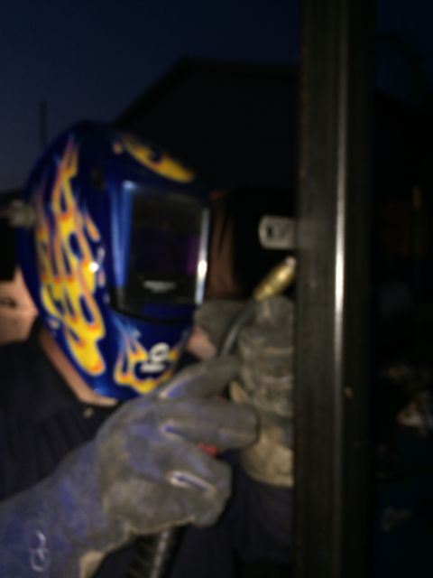 1968 Ford Mustang - A person is welding metal while wearing a flame-patterned welding mask and gloves.