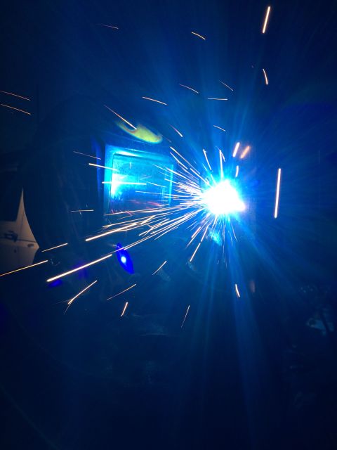 1968 Ford Mustang - A close-up view of a welding process, with numerous bright sparks illuminating the dark scene.