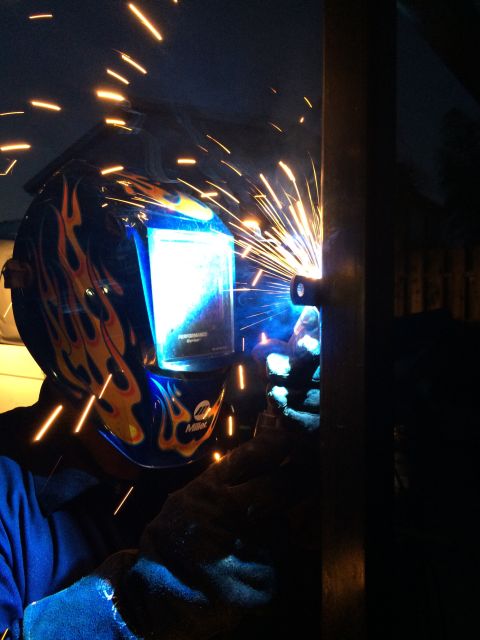 1968 Ford Mustang - A person welds metal, creating a shower of bright sparks against a dark background.