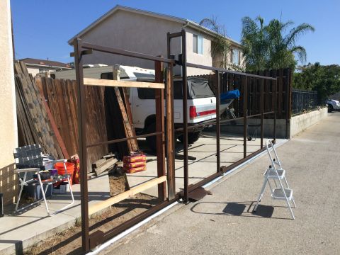 1968 Ford Mustang - A white SUV with a black soft top is parked behind a partially constructed gate.