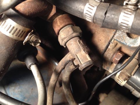 1973 Ford Bronco - Engine bay detail showing a sensor and various hoses, with some rust and wear visible.