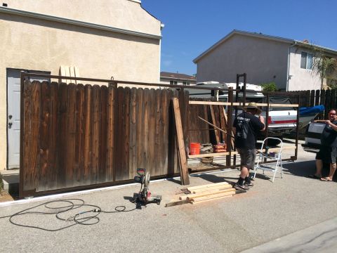 1968 Ford Mustang - People are working on a construction project involving lumber and tools near a wooden fence.