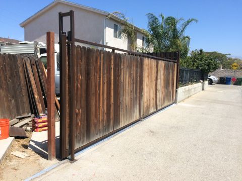 1968 Ford Mustang - A residential driveway with a large wooden gate and some building supplies nearby.