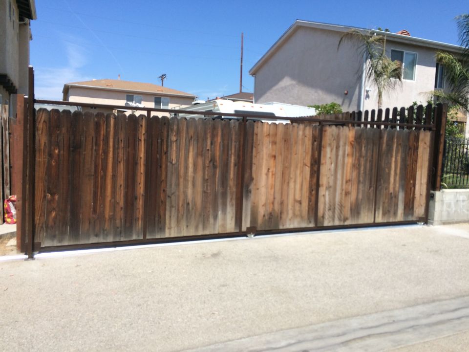 Wooden driveway gate in front of houses