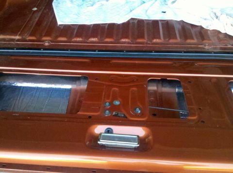 1982 Ford Bronco - The interior of the tailgate is visible, with insulation and the latch assembly exposed.