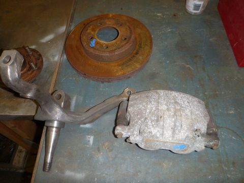 1964 Mercury Monterey - Suspension components including a spindle, brake rotor, and caliper are laid out on a workshop surface.