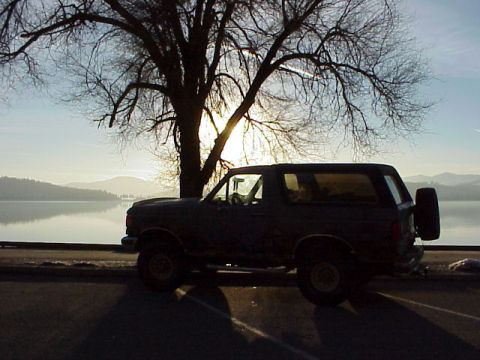 1989 Ford Bronco - Side view of a 1989 Ford Bronco parked near a body of water during sunset.
