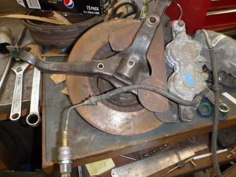 1964 Mercury Monterey - A disassembled suspension component, including a brake rotor and caliper, rests on a workbench alongside tools.