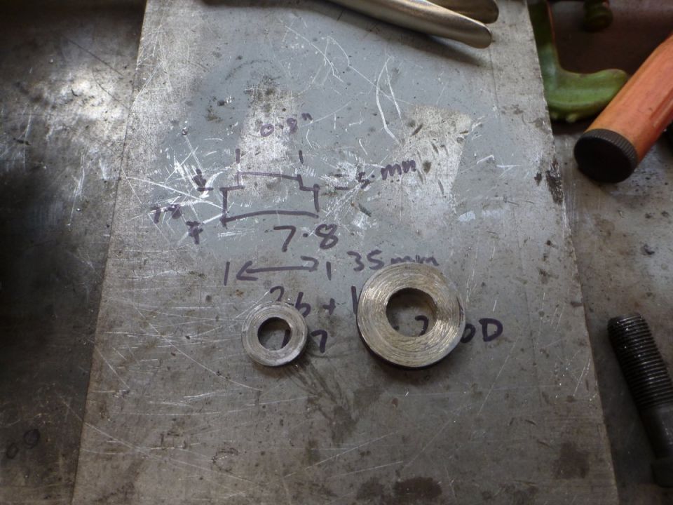 Two washers on a metal surface with handwritten measurements and diagrams