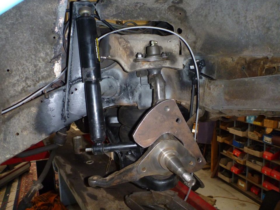 Close-up of a vehicle's front suspension assembly, showing a shock absorber, control arm, and spindle
