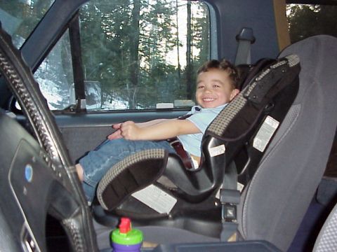 1989 Ford Bronco - A young child smiles from a car seat, with a view of trees and snow outside the window.