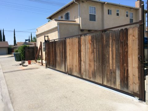 1968 Ford Mustang - A wooden sliding gate stands in front of a two-story beige house with a paved driveway.